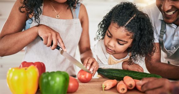 Child watching as parents cut up vegetables